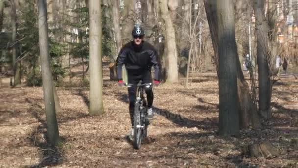 Het pad bezaaid met herfst bladeren, man op de fiets langs — Stockvideo