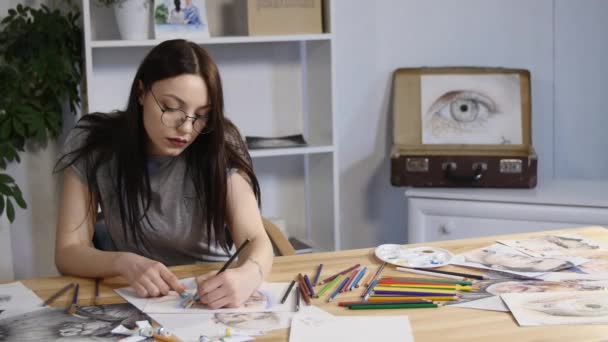 Attraktiva flicka i glasögon drar drar ett porträtt med pennor — Stockvideo