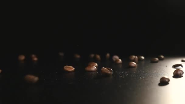 Kaffeebohnen - fallend. eine Makroaufnahme von Kaffeebohnen mit 96 fps, die auf eine schwarze Oberfläche fallen. eine schöne allgemeine Aufnahme für alle Kaffeethemen oder Titelhintergründe — Stockvideo