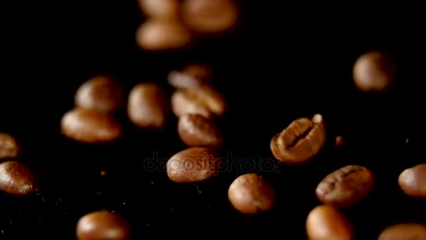 Granos de café - Caída. Una macro toma de 96 FpS de granos de café cayendo sobre la superficie negra. Un tiro genérico hermoso para cualquier tema relacionado con el café o fondos de título — Vídeo de stock