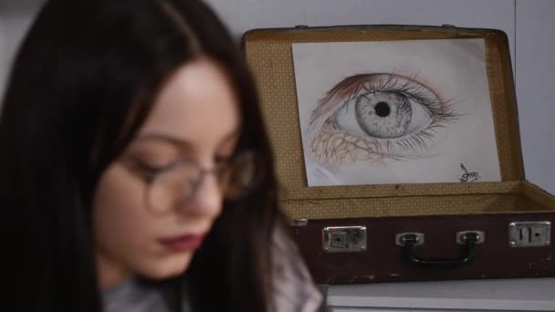 La pintora está trabajando en un boceto mientras está sentada en su oficina. Lleva gafas. — Vídeos de Stock