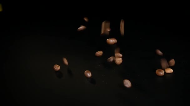 Coffee Beans - Falling. A 96 FpS macro shot of coffee beans falling on black surface. A beautiful generic shot for any coffee related themes or title backgrounds — Stock Video