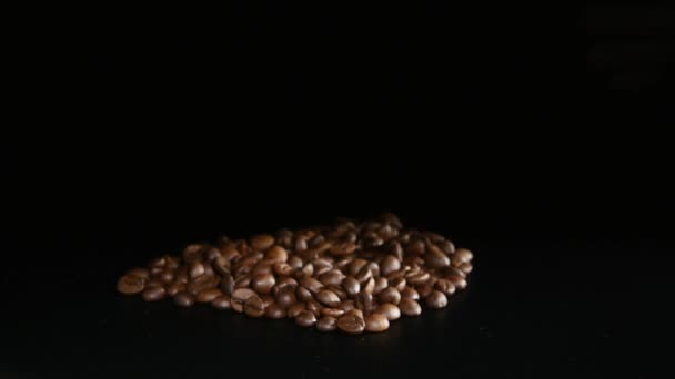 Жареный кофе в зернах вращаются на черном фоне — стоковое видео