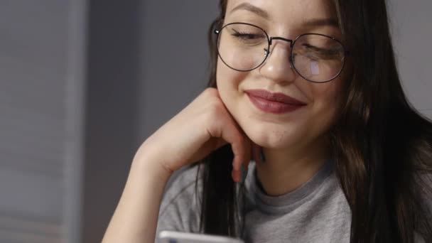 Mujer joven con gafas de navegación fotos en el teléfono inteligente. reflejado en las gafas — Vídeos de Stock