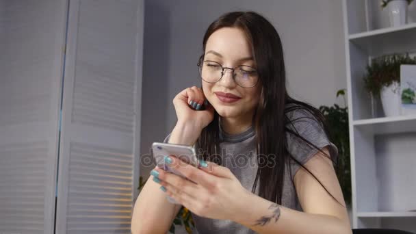 Jonge vrouw met glazen doorbladeren van foto's op smartphone. weerspiegeld in de glazen — Stockvideo