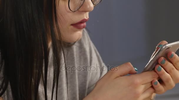 Junge Frau mit Brille, die Fotos auf dem Smartphone durchblättert. spiegelt sich in der Brille wider — Stockvideo