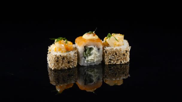 Três diferentes sushi no fundo preto girando — Vídeo de Stock