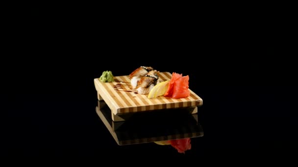 Sushi rolt set op een houten bord. roterende op zwart backround — Stockvideo