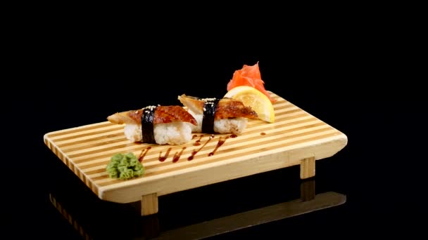 Sushi tekercs készlet egy fából készült hajón. forgó fekete backround — Stock videók