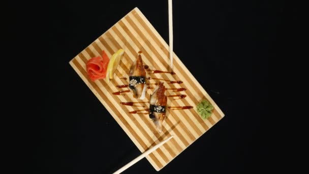 Sushi-Set rotiert auf schwarzem Hintergrund. Ansicht von oben — Stockvideo