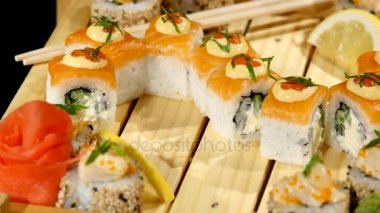 Ahşap bir gemide ayarla suşi rulo yakın çekim. üzerinde siyah artalanları döndürme