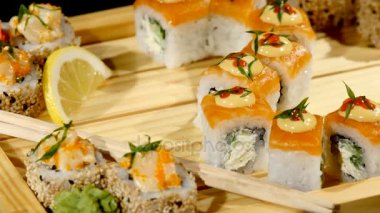 Ahşap bir gemide ayarla suşi rulo yakın çekim. üzerinde siyah artalanları döndürme