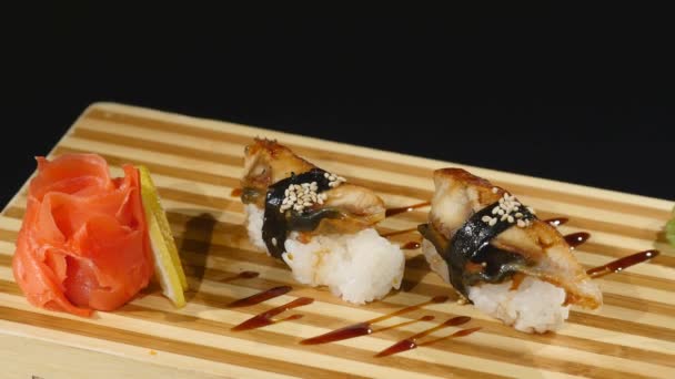 Sushi rullar uppsättningen på en träskiva. roterar på svart bakrund — Stockvideo