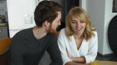 Aşık güzel çift daire sabah keyfini çıkarın. Genç aile kahvaltı portakal suyu içiyor. Çekici kadın mutfakta yakışıklı adam ile konuşma