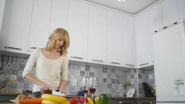 Mulher jovem cortando legumes na cozinha — Vídeo de Stock