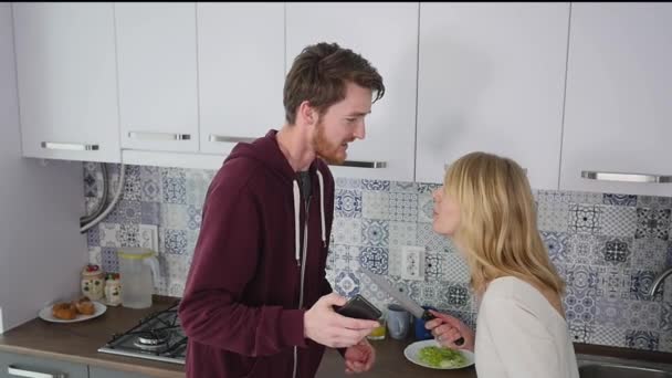 Jóvenes peleas de pareja en la cocina. El hombre y la mujer gritan en frustración y gesticulan furiosamente — Vídeo de stock