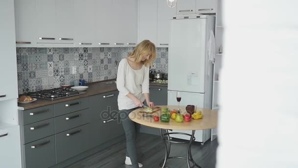 Cara amoroso abraçando sua namorada sorridente em sua cozinha no início da manhã com café da manhã sendo feito em câmera lenta — Vídeo de Stock