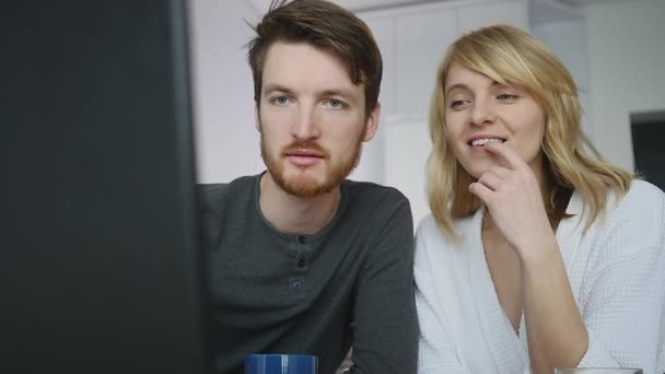 Casal jovem conversando sobre laptop durante o café da manhã na cozinha — Vídeo de Stock