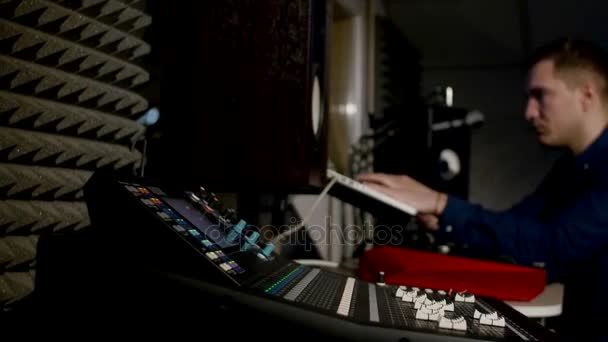 レコーディング スタジオのミキシング ・ デスクでノート パソコンを使用しての 4 k の若いサウンド エンジニア — ストック動画