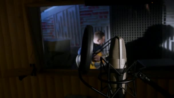 Микрофон на стойке, расположенной в музыкальной студии звукозаписи, под лампочкой с низким ключом — стоковое видео