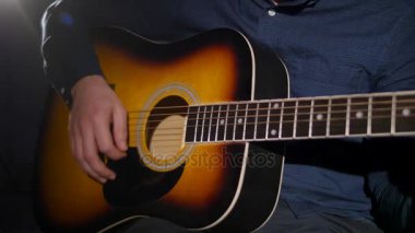 Akustik gitar koyu arka planı stüdyosunda oynayan genç adam