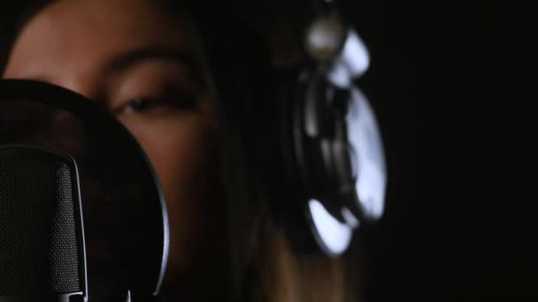Певица в наушниках против микрофона — стоковое видео
