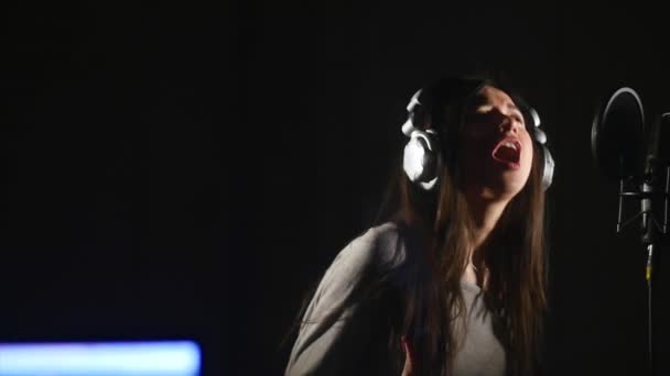 Estudio de grabación de audio. Mujer con auriculares y micrófono de estudio cantando . — Vídeo de stock