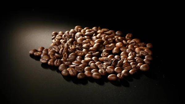 Rostade kaffebönor rotera på svart bakgrund — Stockfoto