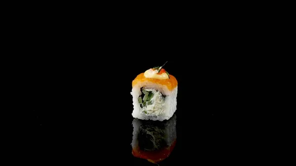 Суши ролл с лосося и икры на черном фоне вращается — стоковое фото