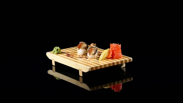 Sushi rolls set on a wooden board. rotating on black backround — Stock Photo, Image