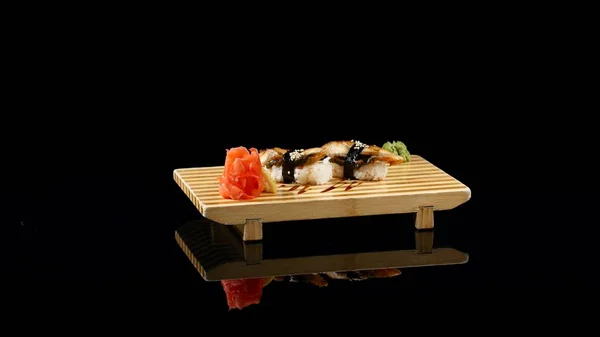 Суши-роллы на деревянной доске. вращение на черном фоне — стоковое фото