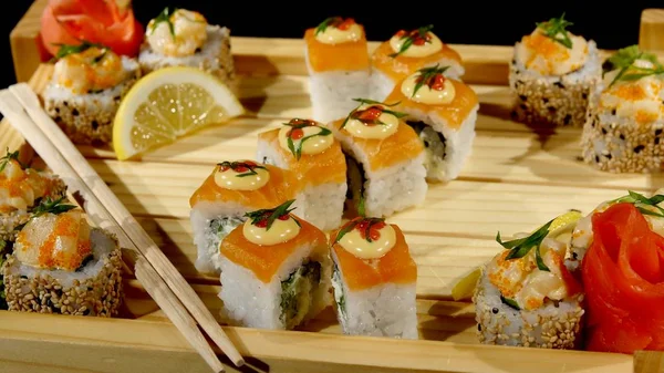 Sushi rolls set on a wooden board. rotating on black backround — Stock Photo, Image