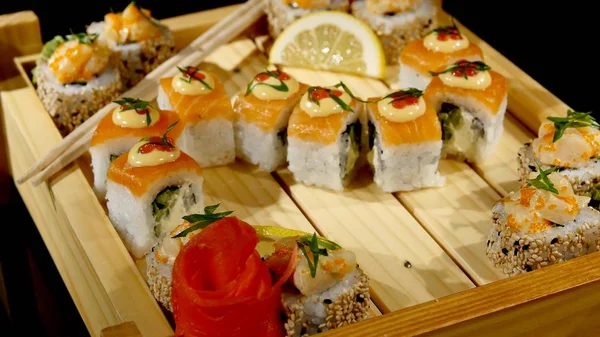 Sushi rullar uppsättningen på en träskiva. roterar på svart bakrund — Stockfoto