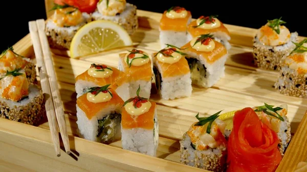 Sushi rullar uppsättningen på en träskiva. roterar på svart bakrund — Stockfoto