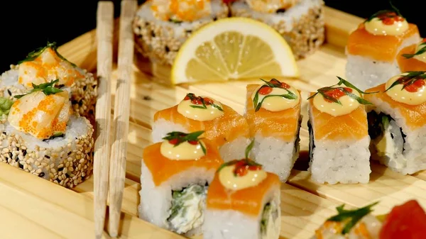 Sushi rullar på en träskiva på nära håll. roterar på svart bakrund — Stockfoto