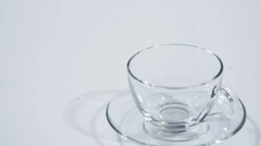 Şeffaf cam bardakta çay yaprakları düşer. Ağır çekim