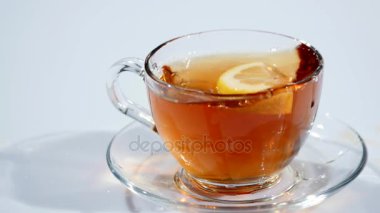 Bir fincan siyah çay bir fincan tabağı üzerinde yavaş mo, beyaz bir arka plan bir dilim limon düşüyor