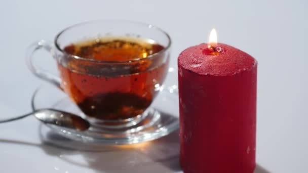 Tasse Tee mit Anzünden roter Kerzen auf weißem Hintergrund — Stockvideo