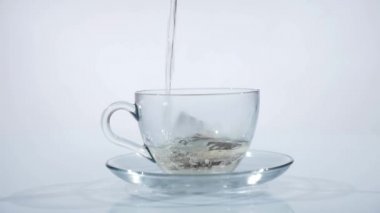 Sıcak çay yapmak için su ile dolu bir cam fincan çay poşeti. Ağır çekim