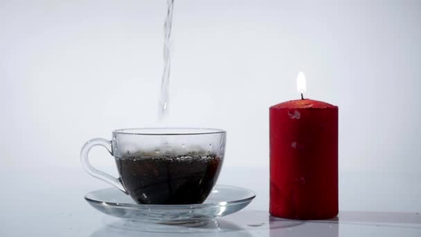 Чашка чая с зажиганием красных свечей на белом фоне — стоковое видео