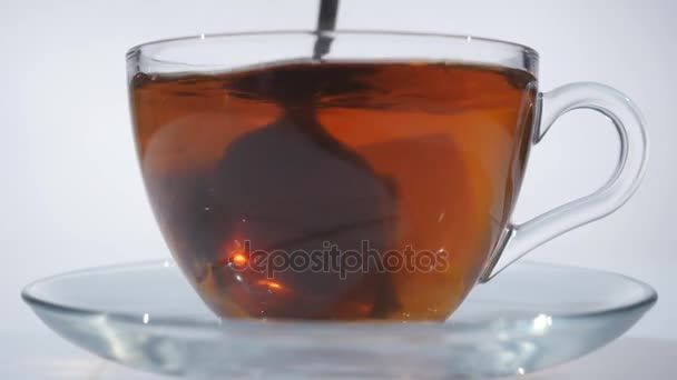 Homme brassant thé avec cuillère dans une tasse en verre 