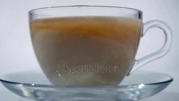Adicionar leite ao chá preto em uma caneca de vidro, close-up — Vídeo de Stock