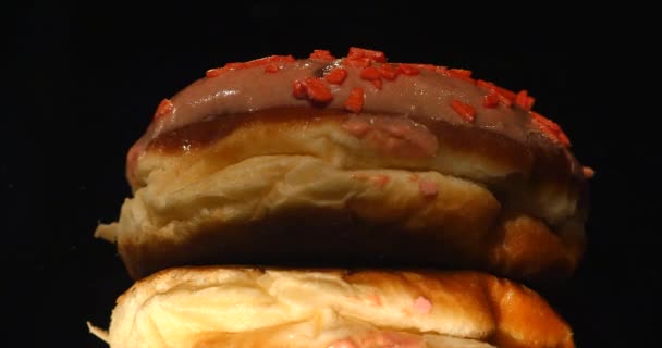 4K footage of glazed sweet donut with sprinkles, rotating with normal speed, isolated on black background — Stock Video