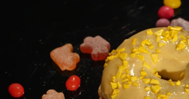 4k Filmmaterial von glasiertem, süßem Donut mit Streusel, der sich mit normaler Geschwindigkeit dreht, isoliert auf schwarzem Hintergrund — Stockvideo