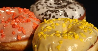 Farklı dolguları ile sırlı donuts bir siyah arka plan üzerinde döndürme