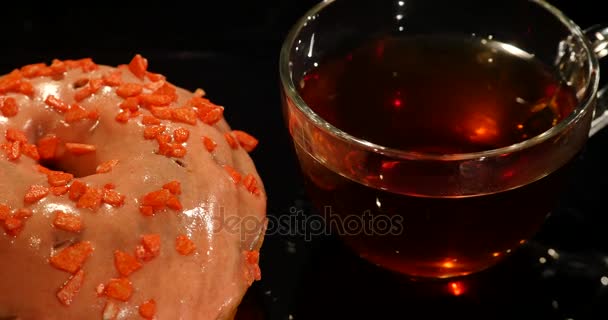 Donuts coloridos e xícara de chá em uma mesa preta — Vídeo de Stock