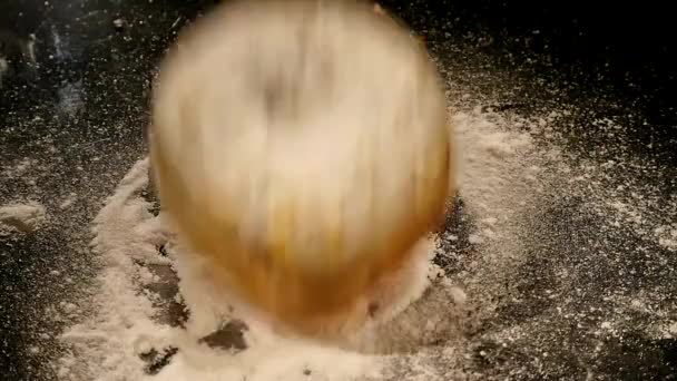 Um donut com um pó de açúcar cai sobre uma mesa preta — Vídeo de Stock