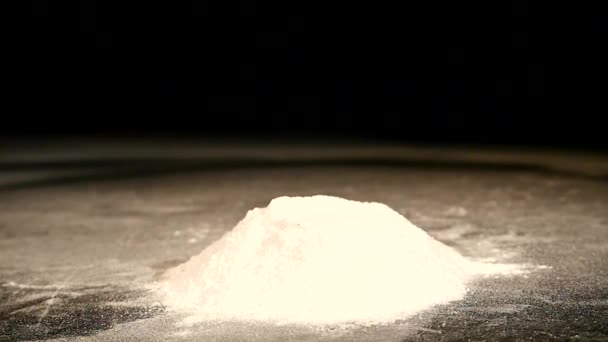 Un beignet avec une poudre de sucre tombe sur un bureau noir — Video