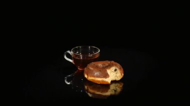 Bardak çay ve çikolata Lokmalar siyah bir arka plan üzerinde döndürme