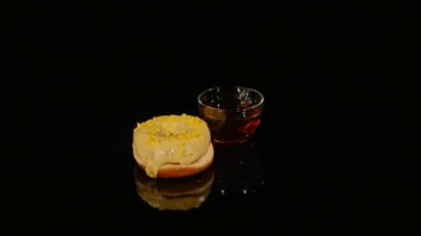 Bardak çay ve çörekler sarı sır ile siyah bir arka plan üzerinde döndürme